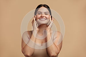 Smiling Woman Touching Face. Woman Smiling While Applying Moisturiser