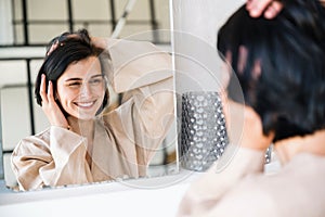 Smiling woman touching healthy hair after washing with professional shampoo