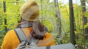 Smiling woman tourist enjoys hiking in autumn forest