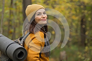 Smiling woman tourist enjoys hiking in autumn forest