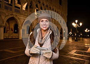 Smiling woman tourist writing sms near Dogi Palace in Venice photo
