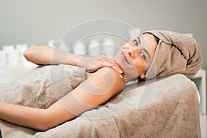 Smiling woman in towel lying on couch in spa salon