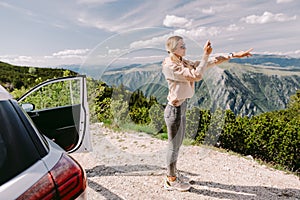 smiling woman travel by car in mountains and taking photos on smartphone