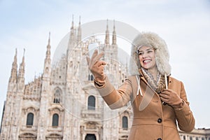 Smiling woman traveller taking selfie with smartphone in Milan