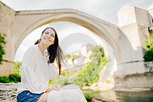 Smiling woman traveller travelling to Southeastern Europe. Visiting local tourist destinations,Old Bridge landmark in Mostar,