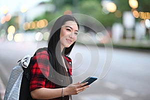 Smiling woman traveller using application of taxi service app on smart phone.