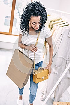 Smiling woman trying trendy handbag in shop