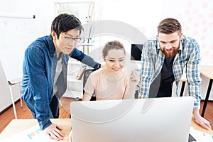 Smiling woman and two men working with computer in office