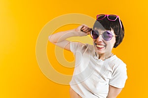 Smiling woman in two pairs of sunglasses. Bright orange background. Happiness concept