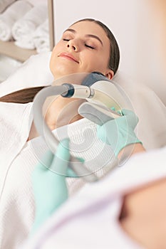 Smiling woman undergoing non-invasive body modeling procedure photo