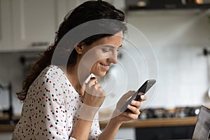 Smiling woman use modern smartphone at home