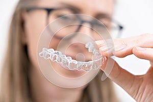 smiling woman using clear plastic removable braces aligner or whitening tray. dental orthodontic care