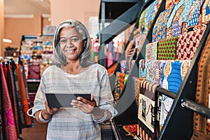 Smiling woman using a digital tablet in her textiles shop