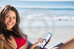Smiling woman using her tablet while relaxing on her deck chair