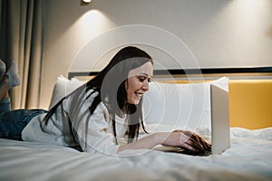 Smiling Woman Using Laptop in Bed