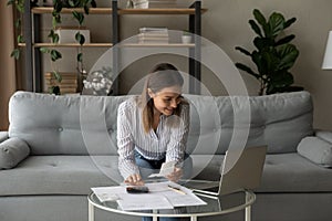 Smiling woman using laptop, managing finances, planning budget at home