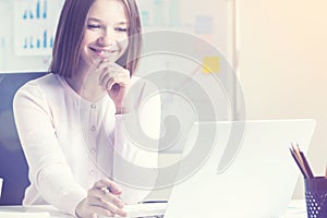 Smiling woman using laptop in office