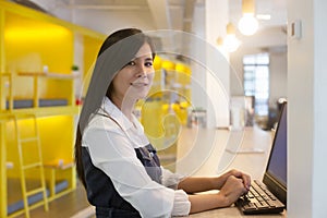 Smiling woman using laptop in work place for small businesses