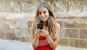 Smiling woman using mobile phone app to play video games online. City woman relaxing. Urban lifestyle. Banner crop for advertising photo