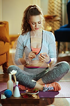 Smiling woman using online yoga training program in smartphone