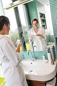 Smiling woman using skin care lotion bathroom