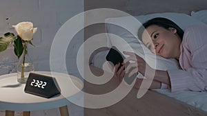 Smiling woman using smartphone on bed