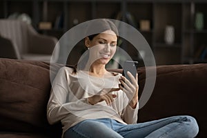 Smiling woman using smartphone, having fun with device at home