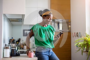 Smiling woman using smartphone in the kitchen at home