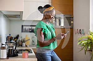 Smiling woman using smartphone in the kitchen at home