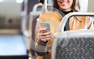 Smiling woman using smartphone in train, subway, bus or tram