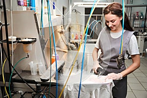 Smiling woman using steam gun and easily removing dirt and stains from clothes