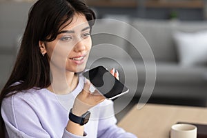 Smiling woman using voice search assistant on smartphone