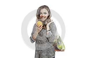 Smiling woman with vegetables in eco bag. Beautiful blonde woman in black leggings and a leopard print shirt with an orange in her