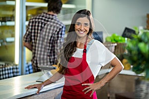 Smiling woman vendor standing at the counter in grocery store