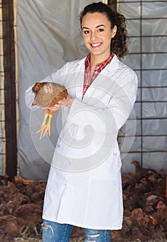 Smiling woman veterinarian holding chicken