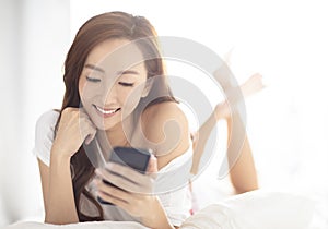 smiling woman watching mobile phone on bed