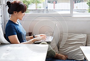 Smiling woman watching video on laptop computer in cozy coworking interior, female student rest during free time reading news blog