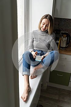 Smiling woman wear headphones using mobile phone talking, listening to podcast or clubhouse.