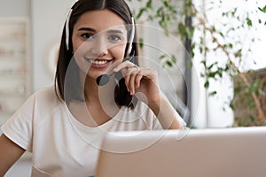 Smiling woman wear headset, watch webinar study, work on laptop, young student in headphones learning computer course