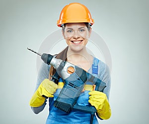 Smiling woman wearing helmet holding drill tool.