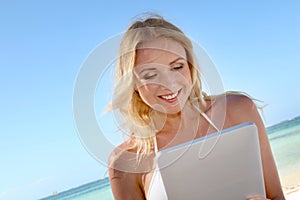 Smiling woman websurfing on the beach