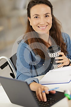 Smiling woman in wheelchair with laptop