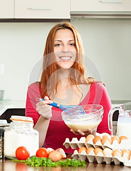 Smiling woman whipping dough in bowl