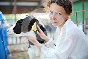 Smiling woman in white robe with small calf looks