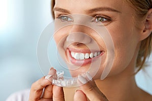 Smiling Woman With White Teeth Holding Teeth Whitening Tray photo