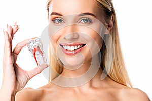 Smiling woman with white teeth holding tooth model isolated on white