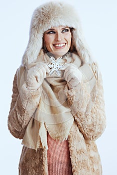 smiling woman in winter coat and fur hat on white