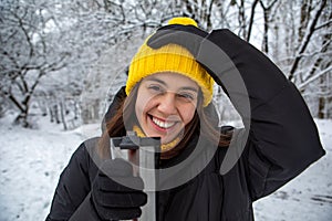 smiling woman in winter outfit drinking warm up drink from refillable mug