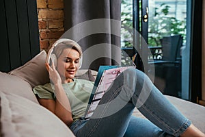 Smiling woman in wireless headphones reading