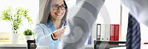 Smiling woman at work table communicates with colleague